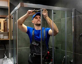 Image jeune-homme-uniforme-repare-porte-douche-dans-salle-bain-reparateur-masculin-repare-cabine-douche